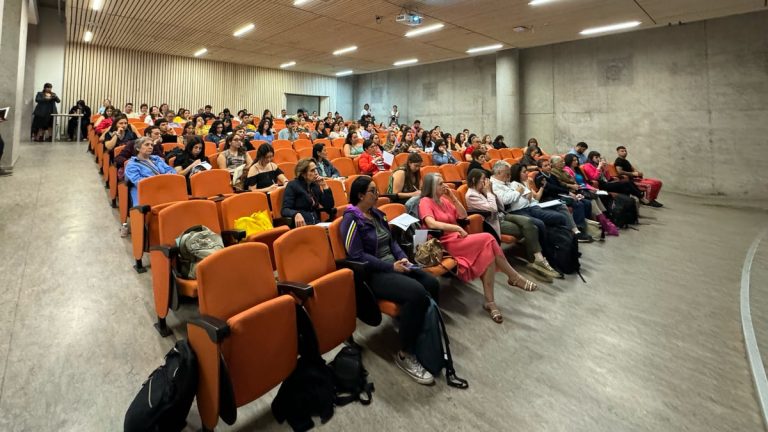 grupo de personas sentadas en asientos color naranjo en una sala de auditorio