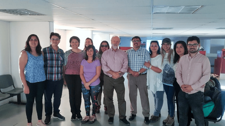 Reunión de equipo con miembros sonrientes en un entorno laboral.